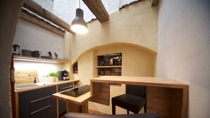 Una cocina compacta con una mesa y banco de madera, una lámpara colgante y un estante empotrado.