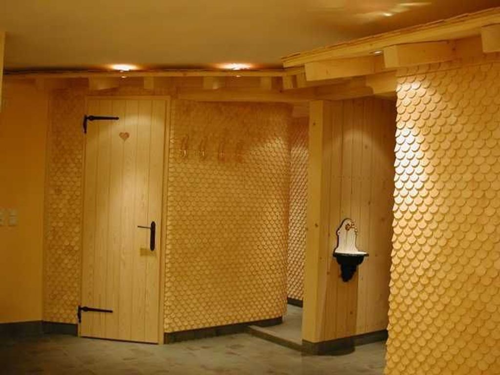 A room with wooden doors, a textured wall, and a small sink.