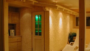 Ein Zimmer mit einem Holzkasten, einer Tür mit einem grünen Licht und einem weißen Stuhl.
