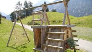 Eine Holzschaukel auf einer Wiese mit Bergblick.