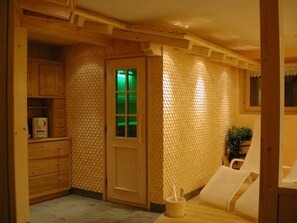A room with a wooden cabinet, a door with a green light, and a white chair.
