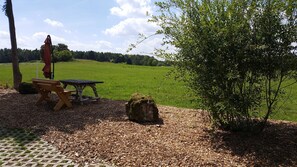 A picnic table and bench in a grassy field with trees in the background. - Apartment Gold - Ferienhof Gold (Waischenfeld)