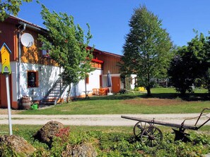 A rustic building with a staircase, outdoor seating, and a wheelbarrow.