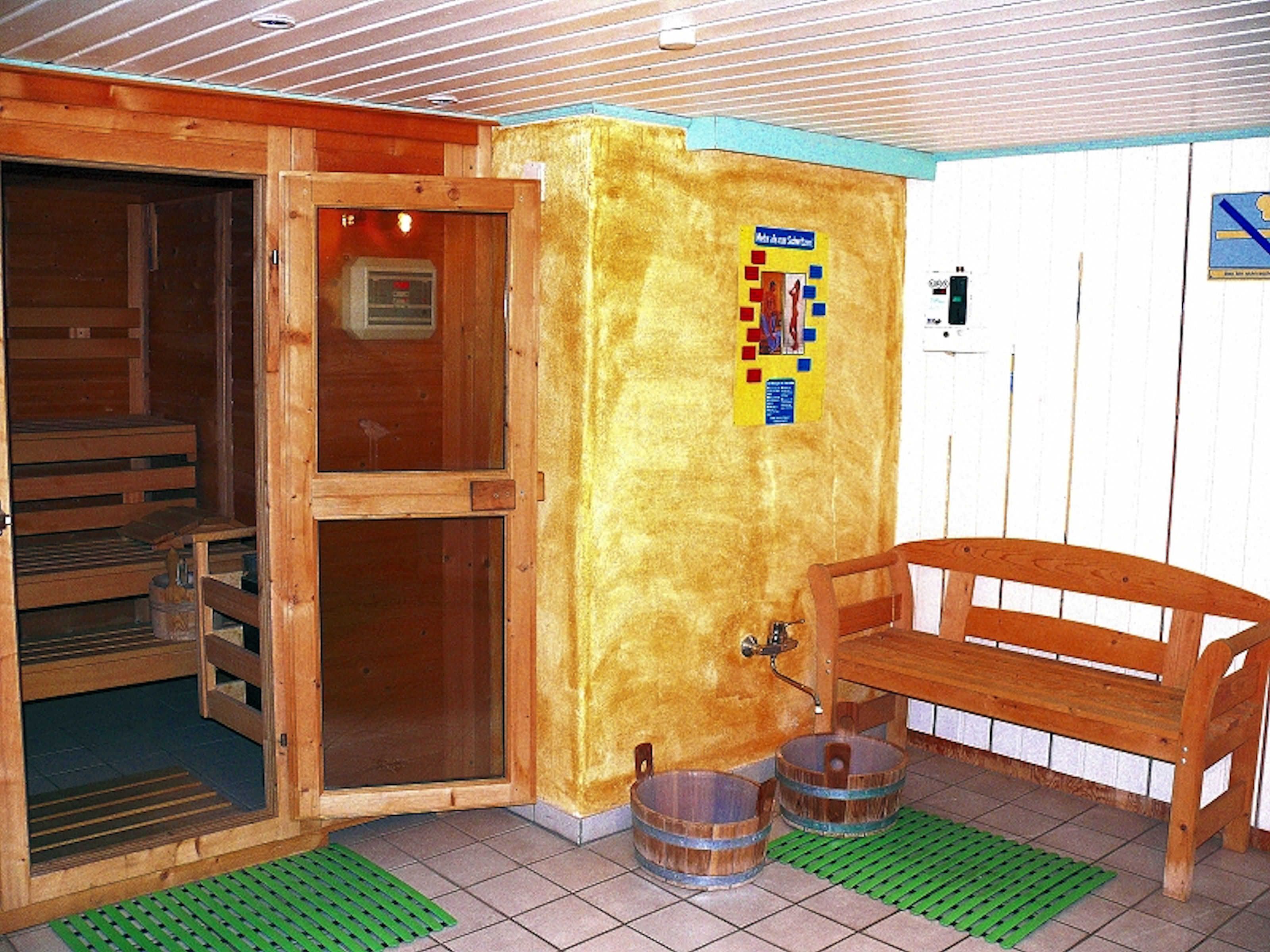 A sauna room with wooden benches, a bench with a towel, and two wooden buckets.