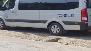 A white van parked in front of a building with a sign that reads "Paradise Hotel Information".