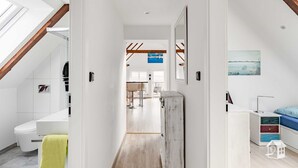 Un interior moderno con una escalera visible, un baño con inodoro y un comedor con sillas y mesa.