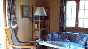 A cozy cabin interior with a wooden ceiling, a sofa set, a plaid rug, and a chair. - Chalet Blettner, Switzerland (Randa VS)