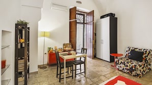 Un espace de vie compact comprenant un coin repas, un canapé, une bibliothèque et un comptoir de cuisine.