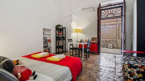 Une pièce comprenant un lit, un bureau et une chaise. Une porte donne accès à un espace extérieur.