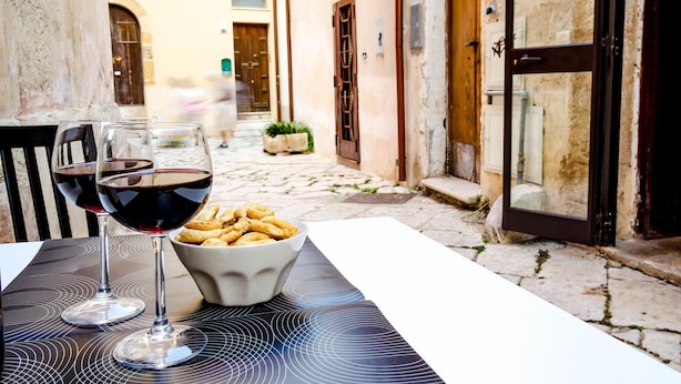 Une table avec deux verres à vin et un bol de collations, le tout installé à l’extérieur.