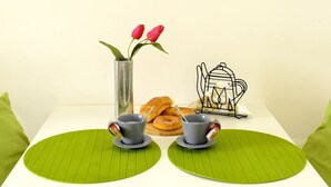 Une table avec deux tasses, un vase rempli de fleurs et un panier de viennoiseries.