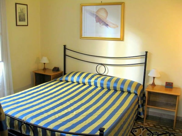 A single bed with a striped bedspread, a headboard with a circular design, two bedside tables with lamps, and a framed picture on the wall. - Luna B&B (Rome)
