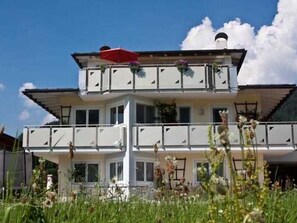 Ein zweistöckiges Gebäude mit Balkonen, einer roten Markise und Blumenkörben.