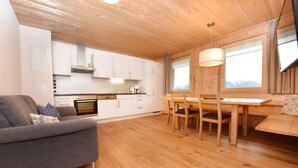Una cocina moderna con armarios blancos, una mesa de comedor con sillas y un sofá.