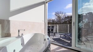 A modern bathroom with a large bathtub and a glass door leading to an outdoor patio area.