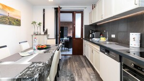 Una cocina moderna con comedor, que presenta una encimera negra, armarios blancos y vista al salón comedor.
