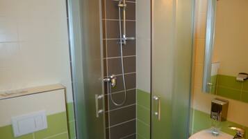 A bathroom with a glass-enclosed shower, a white sink, and a toilet.