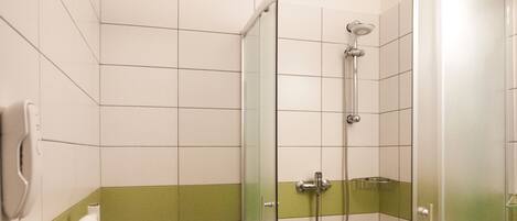 A modern bathroom with a glass-enclosed shower, a toilet, and a sink.