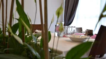 A dining table set with plates, glasses, and a vase with flowers.