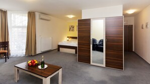 Een hotelkamer met een bed, een houten tafel met fruit, een spiegel en een radiator.