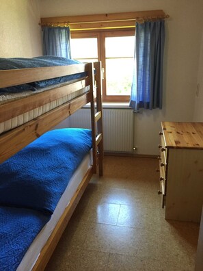 A bunk bed with a wooden ladder, a small wooden dresser, and a window with curtains. - 3rd vacation apartment 2-4 pers. 1 - Küferhof, Matt Sven (Mellau)