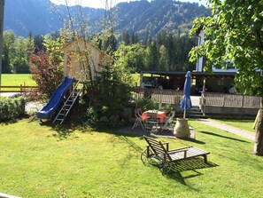 A backyard with a slide, a table with chairs, and a wooden bench. - 3rd vacation apartment 2-4 pers. 1 - Küferhof, Matt Sven (Mellau)
