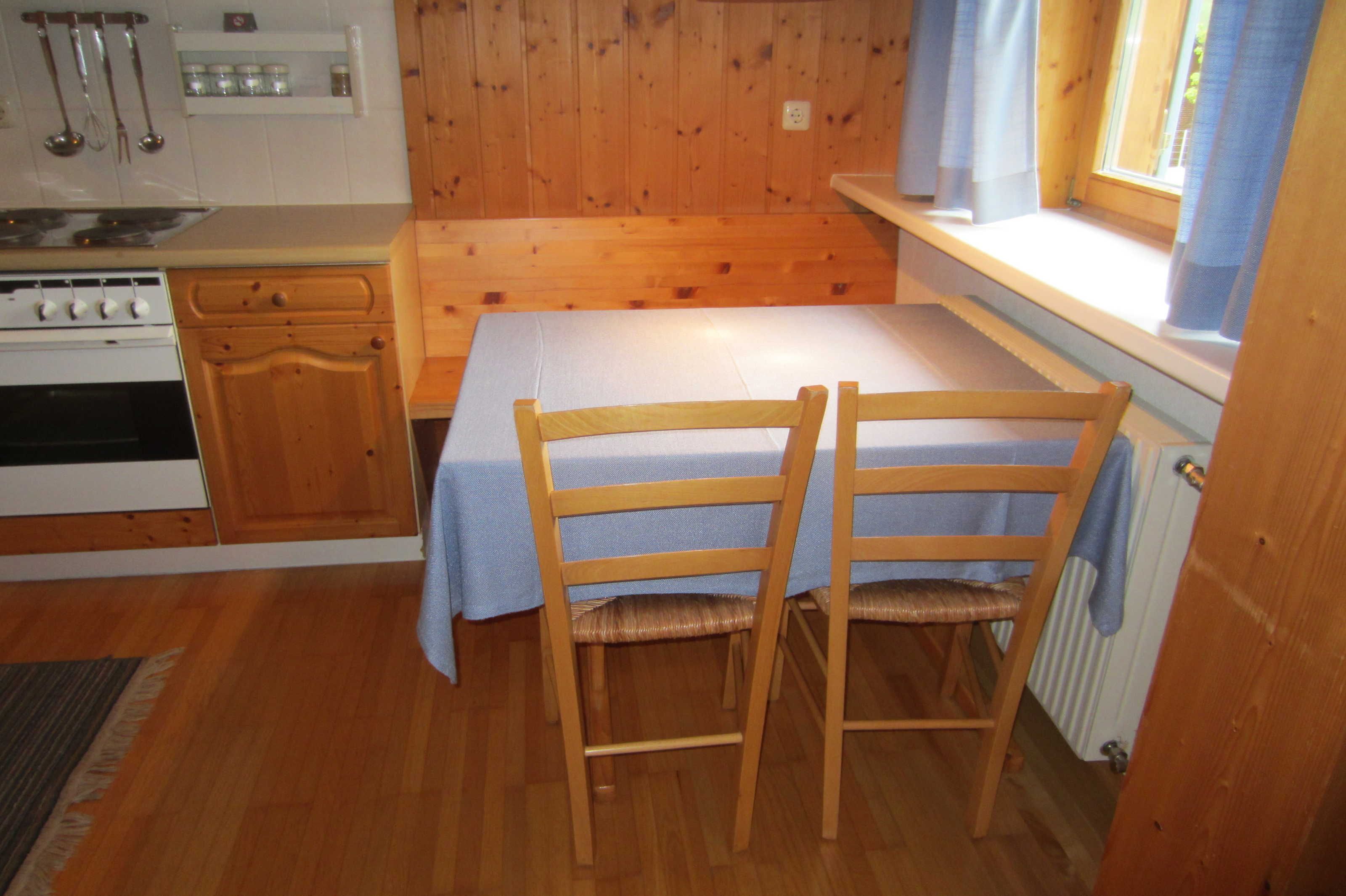 Una cocina pequeña con armarios de madera, estufa y ventana con cortinas.