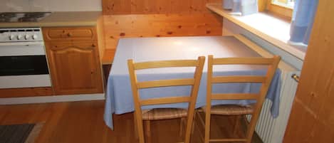 Una cocina pequeña con armarios de madera, estufa y ventana con cortinas.
