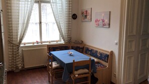 Una habitación de esquina con una mesa, un banco, un radiador y dos cuadros en la pared.