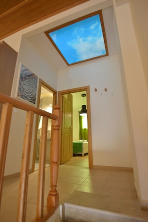Un escalier avec une rampe en bois menant à une pièce dotée d’une lucarne.