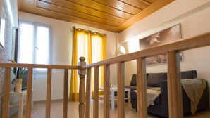 A living room with a wooden staircase, a sofa, a table, and a lamp. - Castello Di Porto (Mylopotamos)