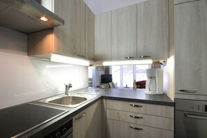 A modern kitchen with a built-in stove, a sink, and a coffee maker.