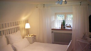 A neatly made bed with white linens, a bedside lamp, and a window with curtains. - Holiday home Klookris 15 (Risum-Lindholm)