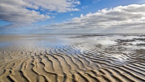 A beach with rippled sand patterns and a partly cloudy sky. - Holiday home Klookris 15 (Risum-Lindholm)