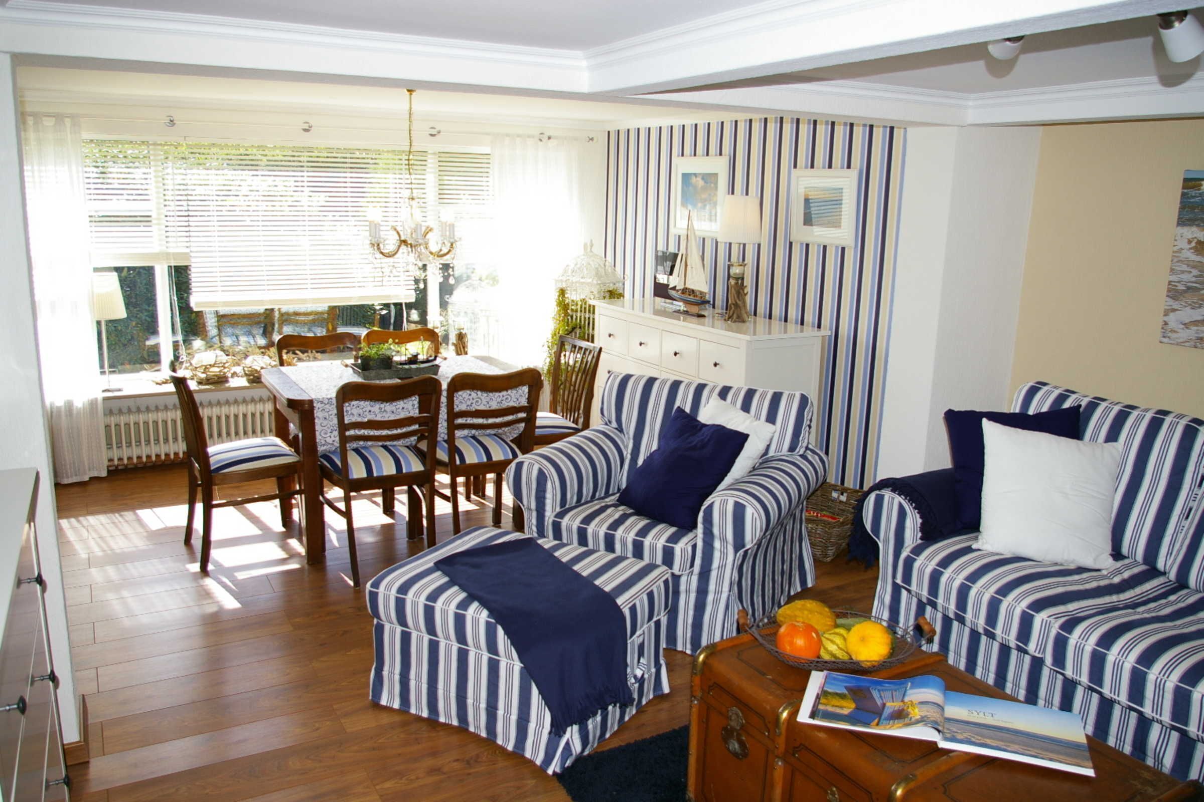 Ein Wohnzimmer mit gestreiften Sofas, einem Esstisch mit Stühlen und einem Holztisch mit Früchten.