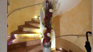 Una escalera con barandilla metálica, un jarrón decorativo con flores y una barandilla.