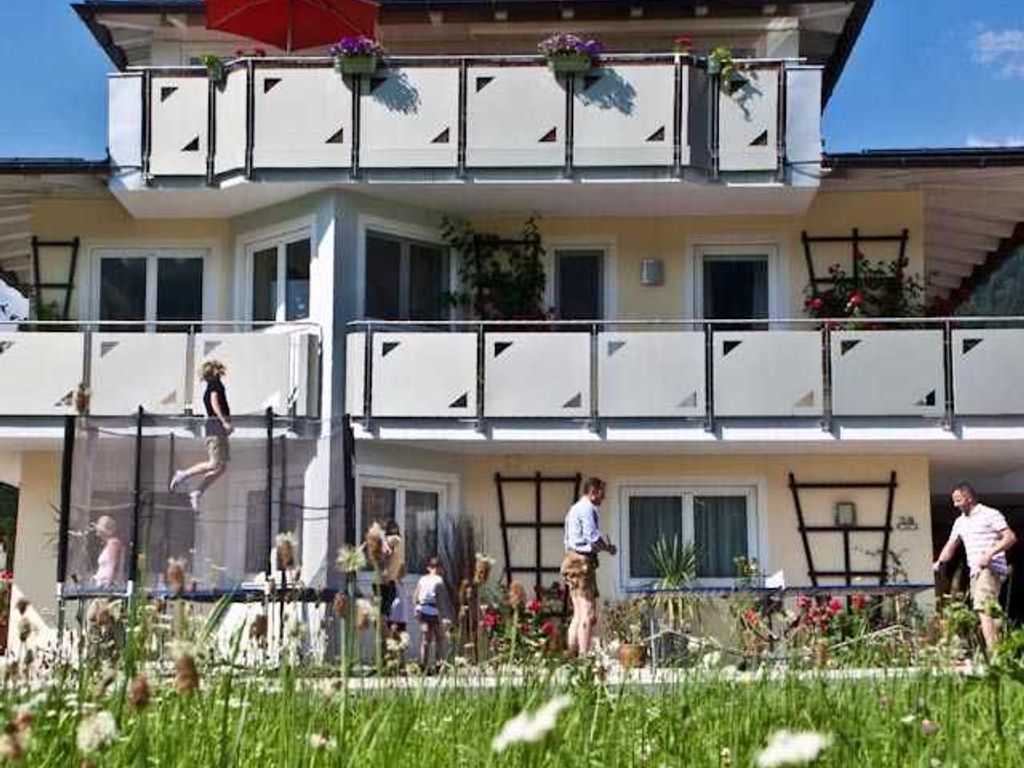 A multi-story building with balconies, a visible window, and a person jumping on a trampoline.