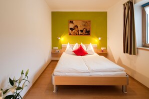 A single bed with white bedding, a green accent wall, and a painting above it. - Top 1 - 3 (3) - Apartment block Charisma (Fieberbrunn)