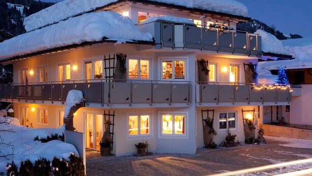 Un edificio de dos pisos con múltiples ventanas y balcones, rodeado de nieve.