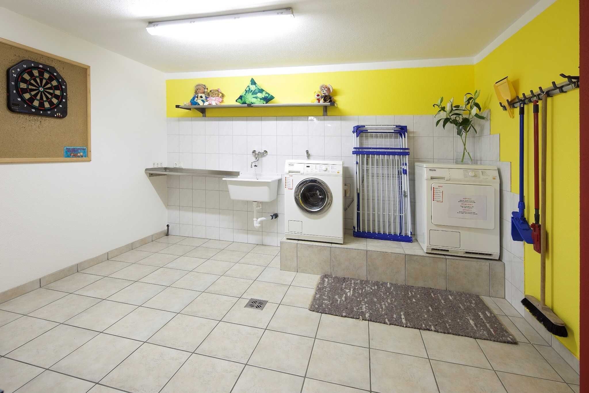 A laundry room with a washing machine, dryer, sink, and a dartboard.