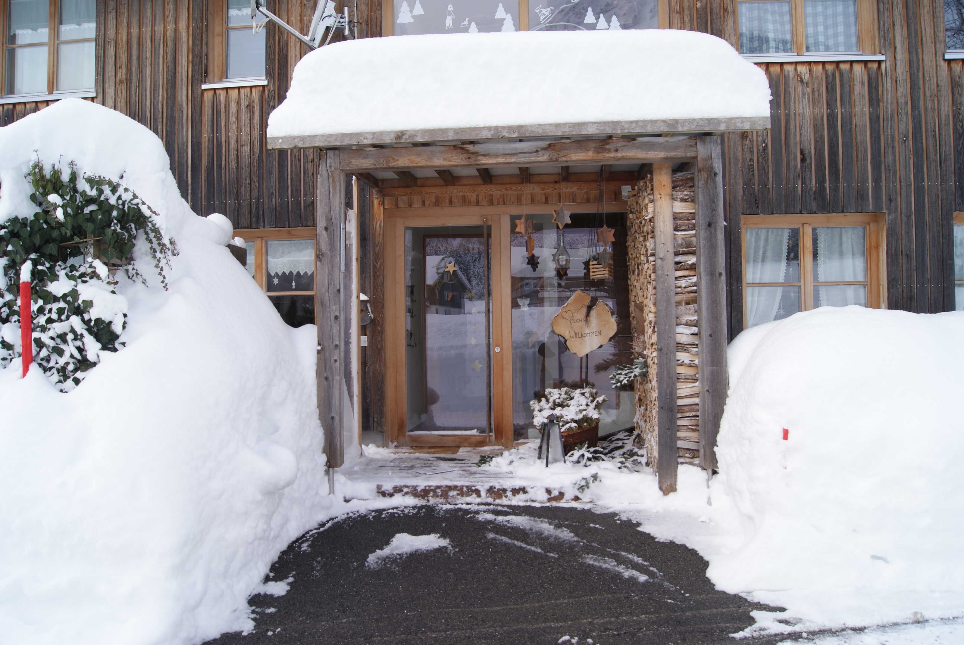 A wooden building with a snow-covered entrance and a wooden sign.