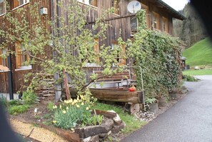 Edificio de madera rústico con jardín, que incluye un banco de madera, un tronco y plantas en macetas.
