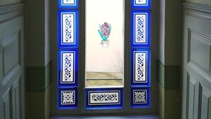 Una porta con pannelli decorativi blu e una pianta in vaso al centro.