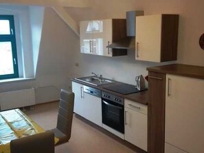 A compact kitchen with a stove, oven, sink, and cabinets. - Apartment IV. First floor (DG), 75m��, 2 bedrooms without balcony - Old Fire Station Görlitz City (Görlitz)