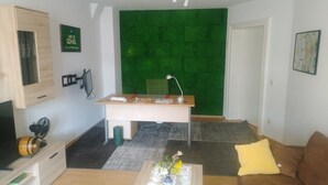 Un soggiorno moderno con una parete verde strutturata, una scrivania in legno, un divano marrone e un tavolino con un vaso.