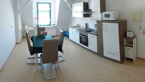 Cucina compatta con mobili bianchi, un forno a microonde e un tostapane. C'è una zona pranzo con tavolo e sedie, e una finestra con vista.