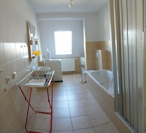 A bathroom with a bathtub, a shower, a sink, and a drying rack.