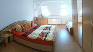 Una camera da letto con un letto a ferro di cavallo, una scrivania, una sedia, un termosifone e una finestra.