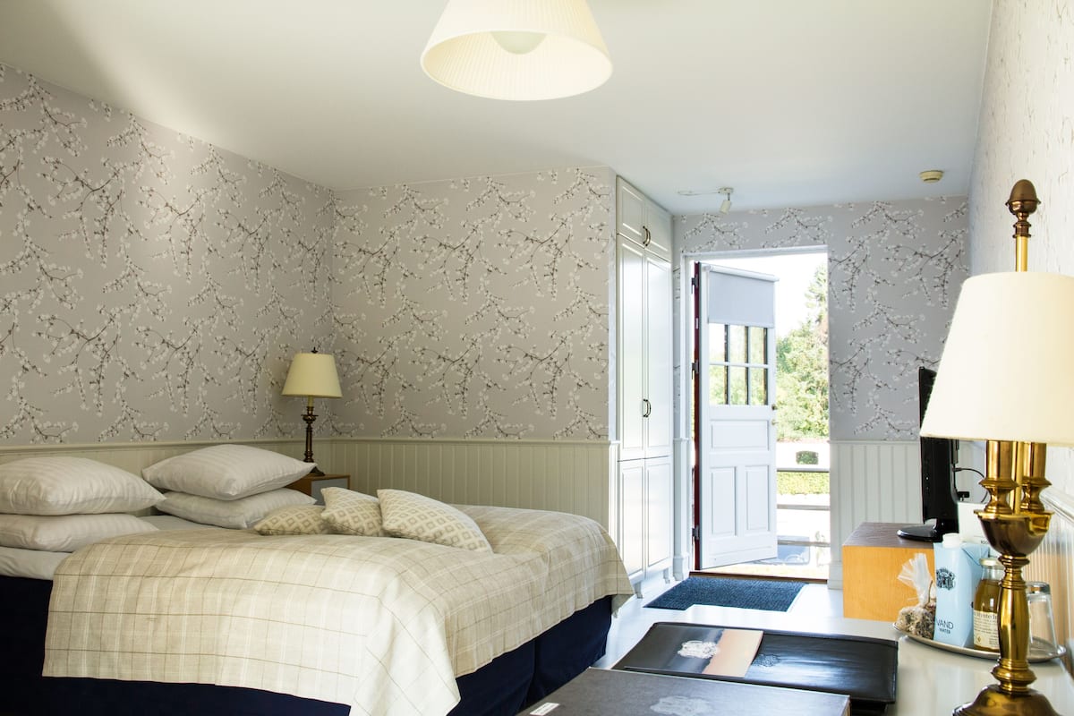 Une chambre à coucher avec un lit, des lampes de chevet, une table de nuit et une vue sur l’extérieur.