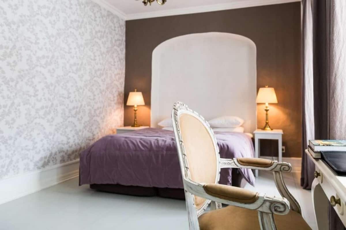 Une chambre à coucher avec un lit, deux lampes de chevet, une chaise et une table de chevet.